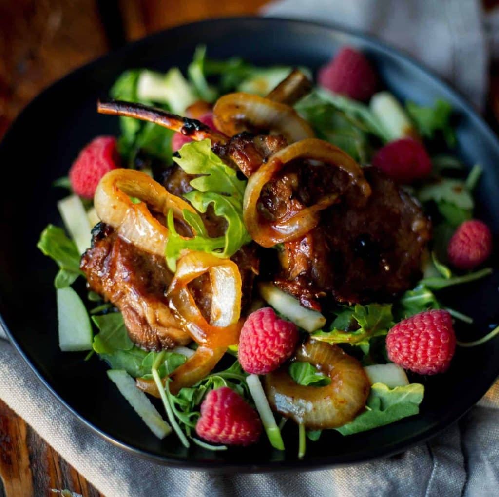 Plat appétissant avec viande, légumes et framboises fraîches.