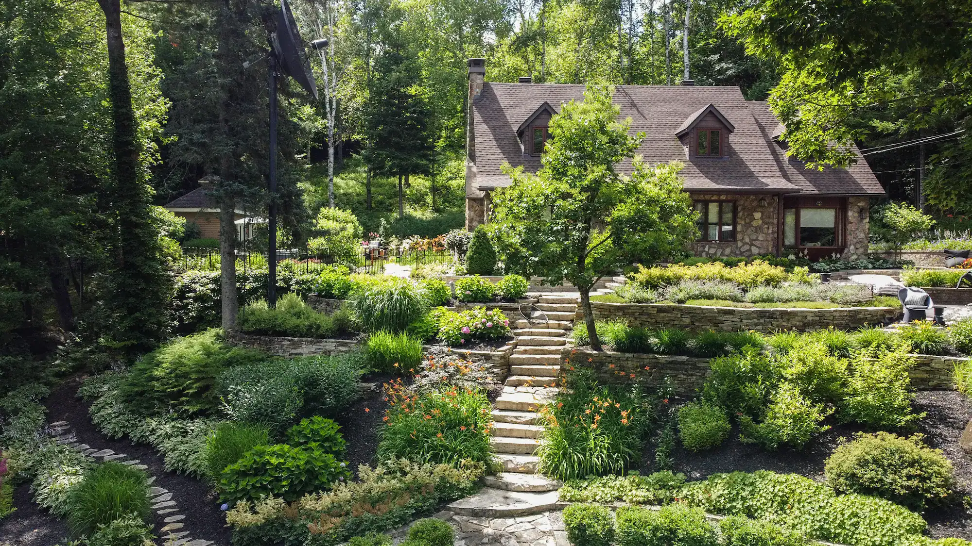 Jardin Dion avec maison en pierre entourée de verdure luxuriante.