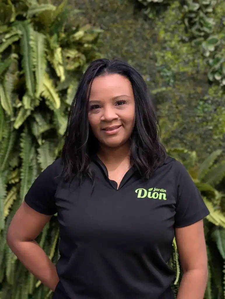 Employée de Jardin Dion en extérieur avec végétation luxuriante.